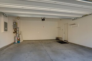 Ett rent, tomt garage med ett betonggolv, en stängd dörr och en projektor som är monterad i taket.