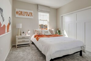 A bedroom with a bed, a nightstand, a lamp, a window with a view, and a door. - New Build w/ Patio! Roseville Extended Stay (Roseville)