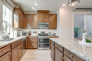 Una cocina con armarios de madera, electrodomésticos de acero inoxidable, encimera de granito y un ventanal amplio.