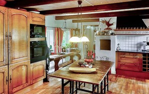 A traditional kitchen with wooden cabinets, a central island, and a hanging light fixture. - Pet friendly home in Borrby with sauna (Borrby)