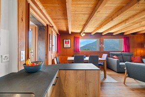 Un intérieur en bois comprenant un coin repas, un canapé et une vue sur l’extérieur.