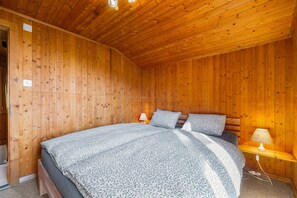 Ein Zimmer mit Holzwandverkleidung, einem Bett, zwei Nachttischlampen und einer Steckdose an der Wand.