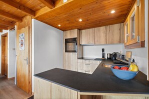 Eine moderne Küche mit Holzschränken, einer schwarzen Arbeitsplatte und einem eingebauten Backofen.