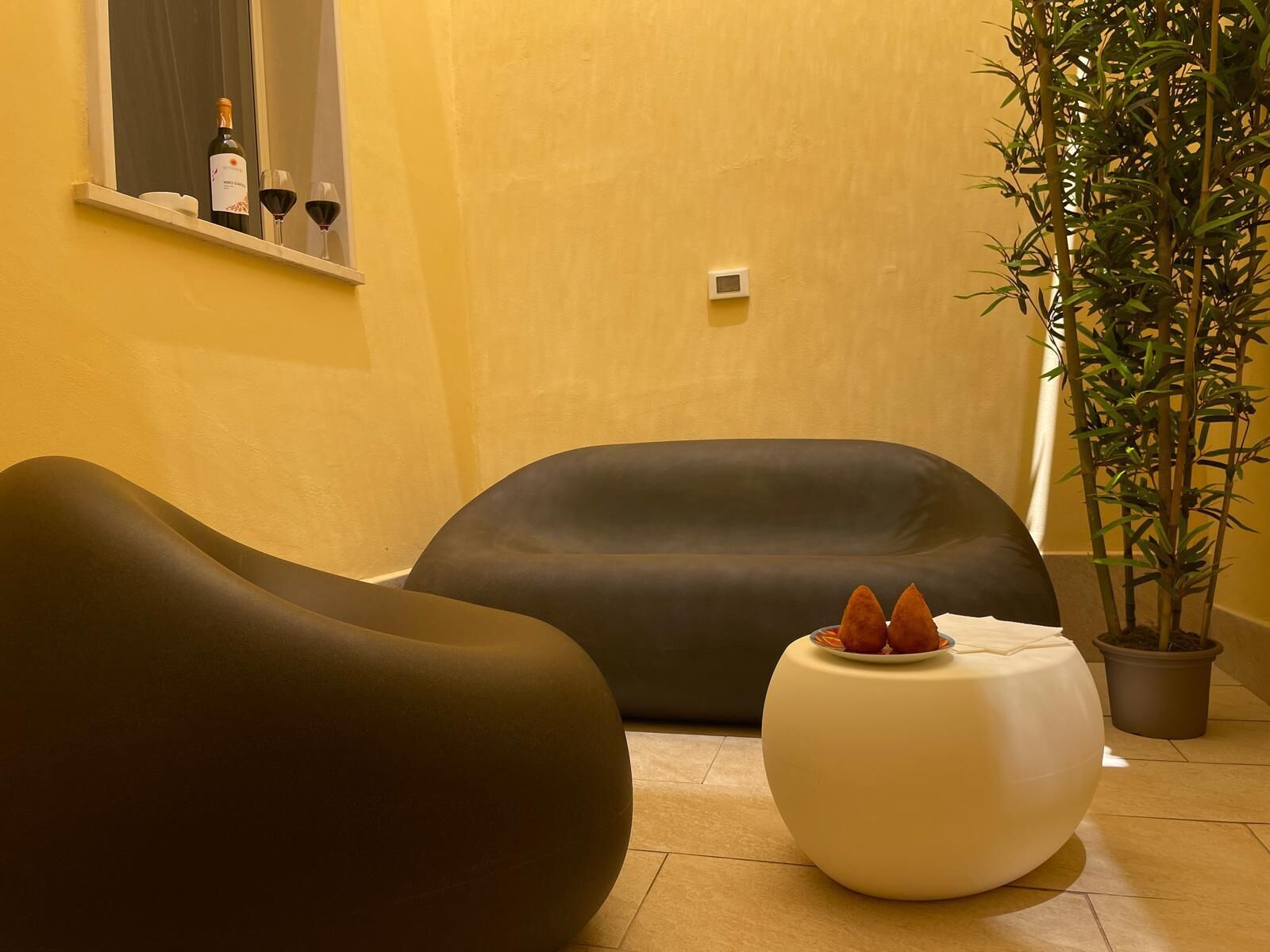 Et moderne interiør med sofa, skærm og en potteplante.
