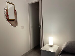 Ein Zimmer mit einem weißen Nachttisch, einem Wandspiegel und einer Tür.