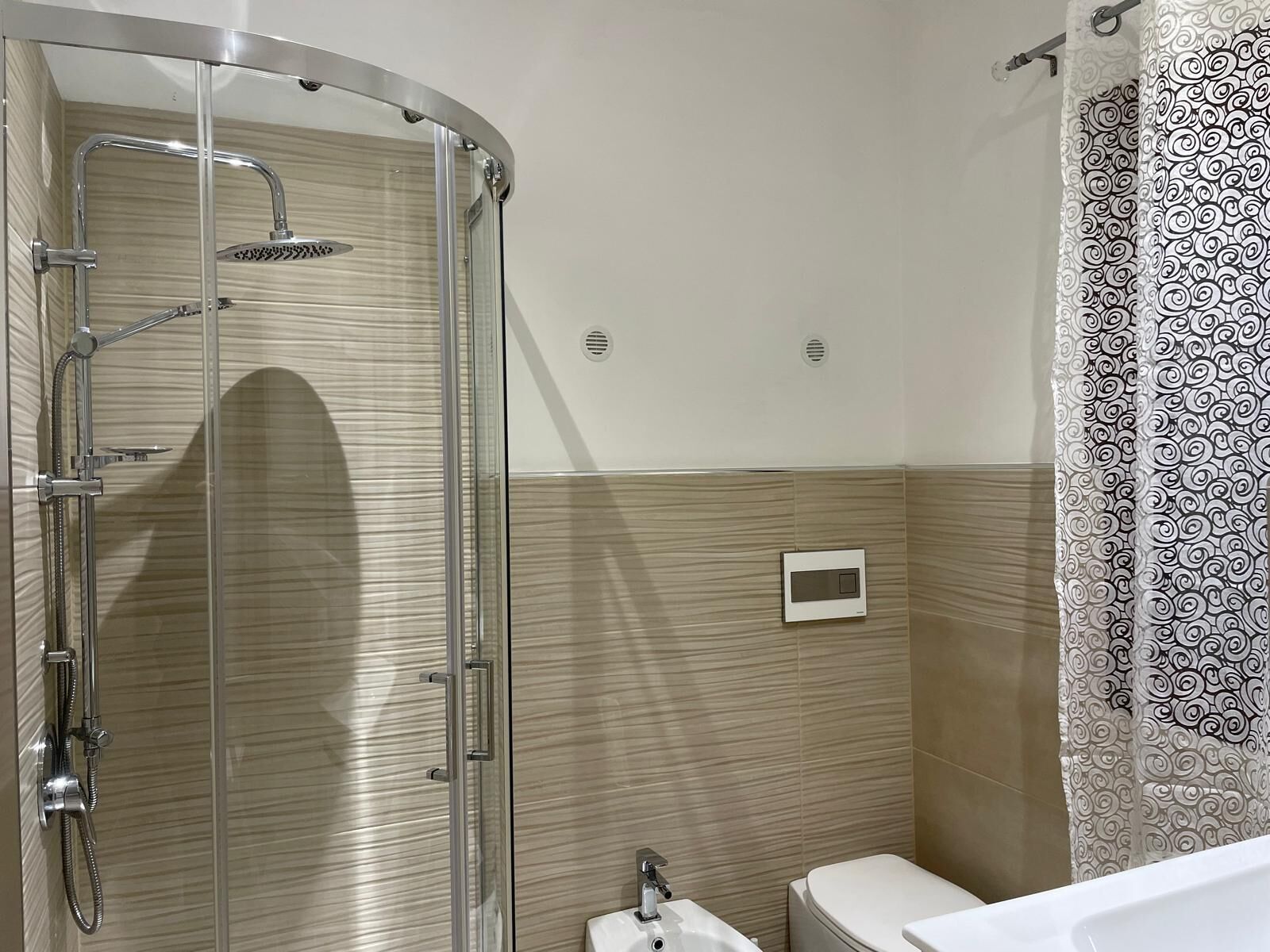 A modern bathroom with a glass-enclosed shower, a toilet, and a sink.