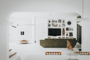 A modern living room with a large flat-screen TV, a sofa, and a coffee table. - Villa Amonita – Luxury Villa, Heated Pool & Private Garden (Tiagua)