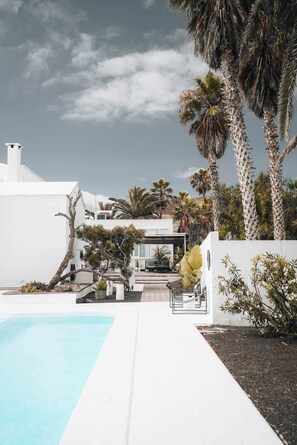 A modern house with a pool, surrounded by palm trees and a clear sky. - Villa Amonita – Luxury Villa, Heated Pool & Private Garden (Tiagua)
