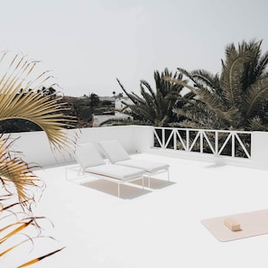 A rooftop terrace with two white lounge chairs and a small table, surrounded by palm trees and a white railing. - Villa Amonita – Luxury Villa, Heated Pool & Private Garden (Tiagua)