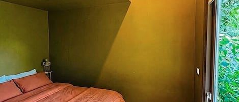 Un dormitorio con cama, ventana y suelo de madera.