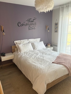 Ein Schlafzimmer mit Bett, Nachttisch, Wandleuchte und dekorativem Wandzeichen.
