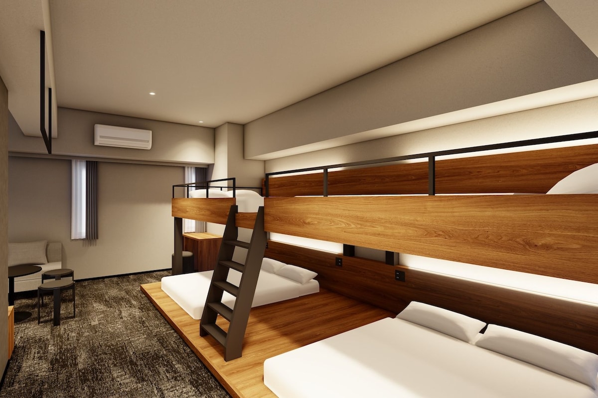 A modern hotel room with bunk beds, a desk, and a small seating area.
