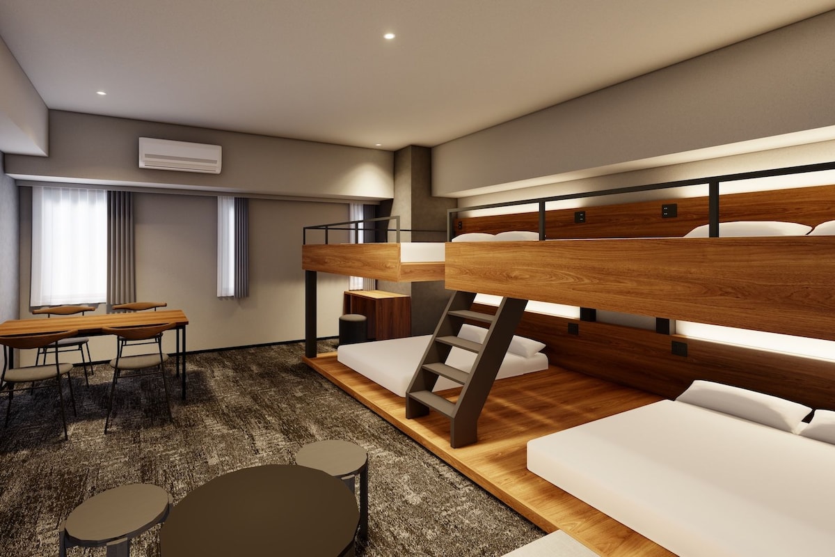 A modern hotel room with bunk beds, a dining table, and a small seating area.
