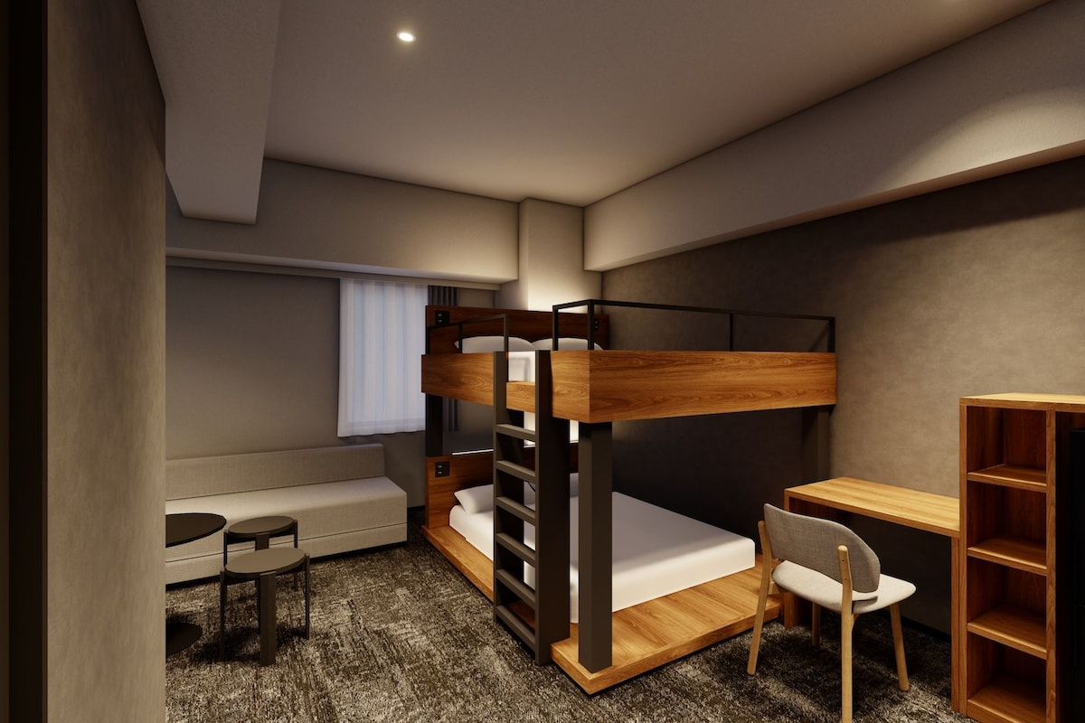 A bunk bed with a desk and chair, a small table, and a bookshelf in a modern room.