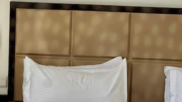 Habitación de hotel con cama, ropa de cama blanca y cabecera con diseño de panel.