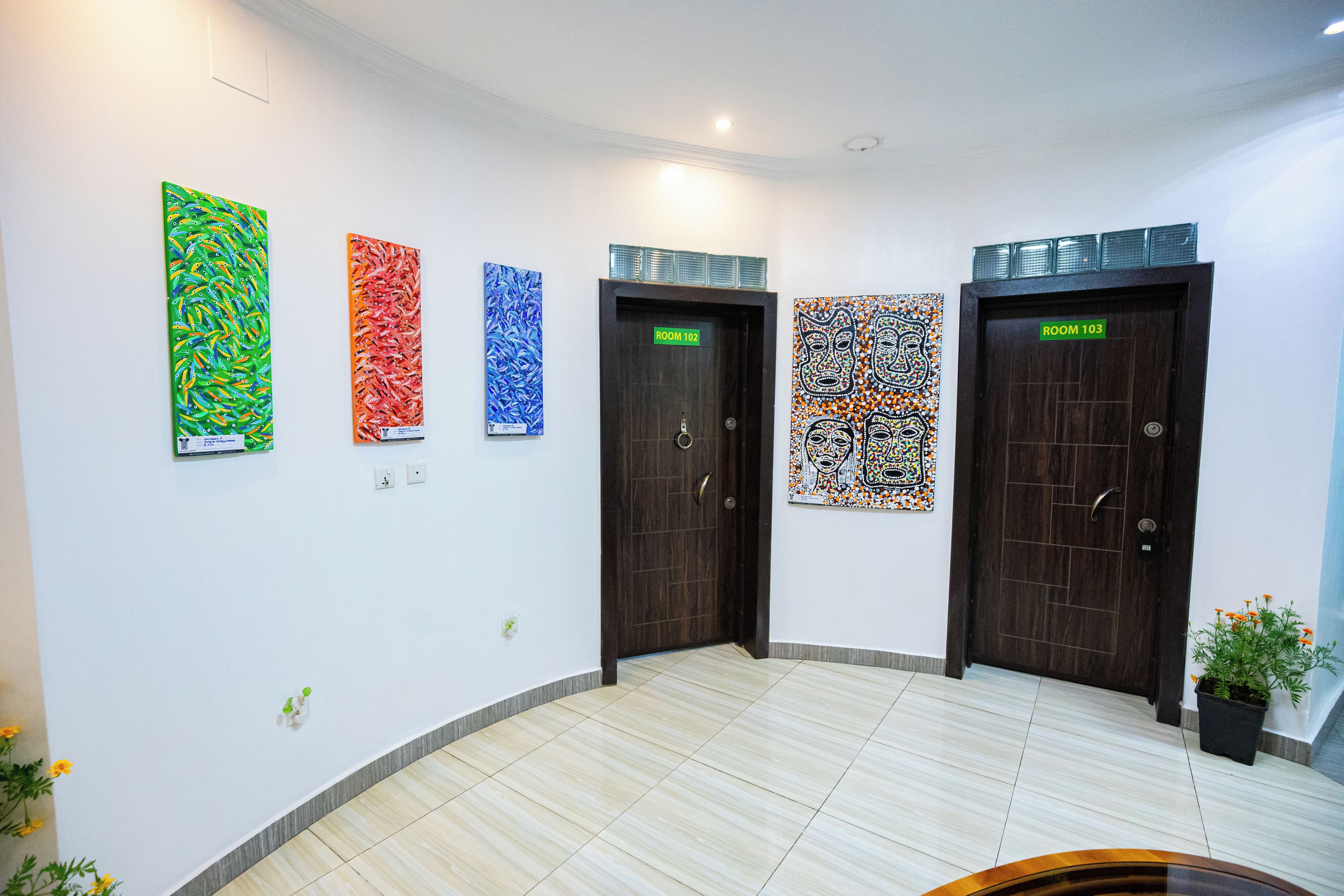 Un pasillo con cuatro puertas, cada una decorada con una obra de arte distinta.