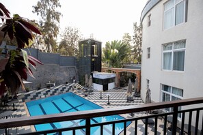 A swimming pool with a chevron pattern, surrounded by outdoor seating and a small building labeled 'The Art Corner.' - Eagle View Kimi (Kigali)