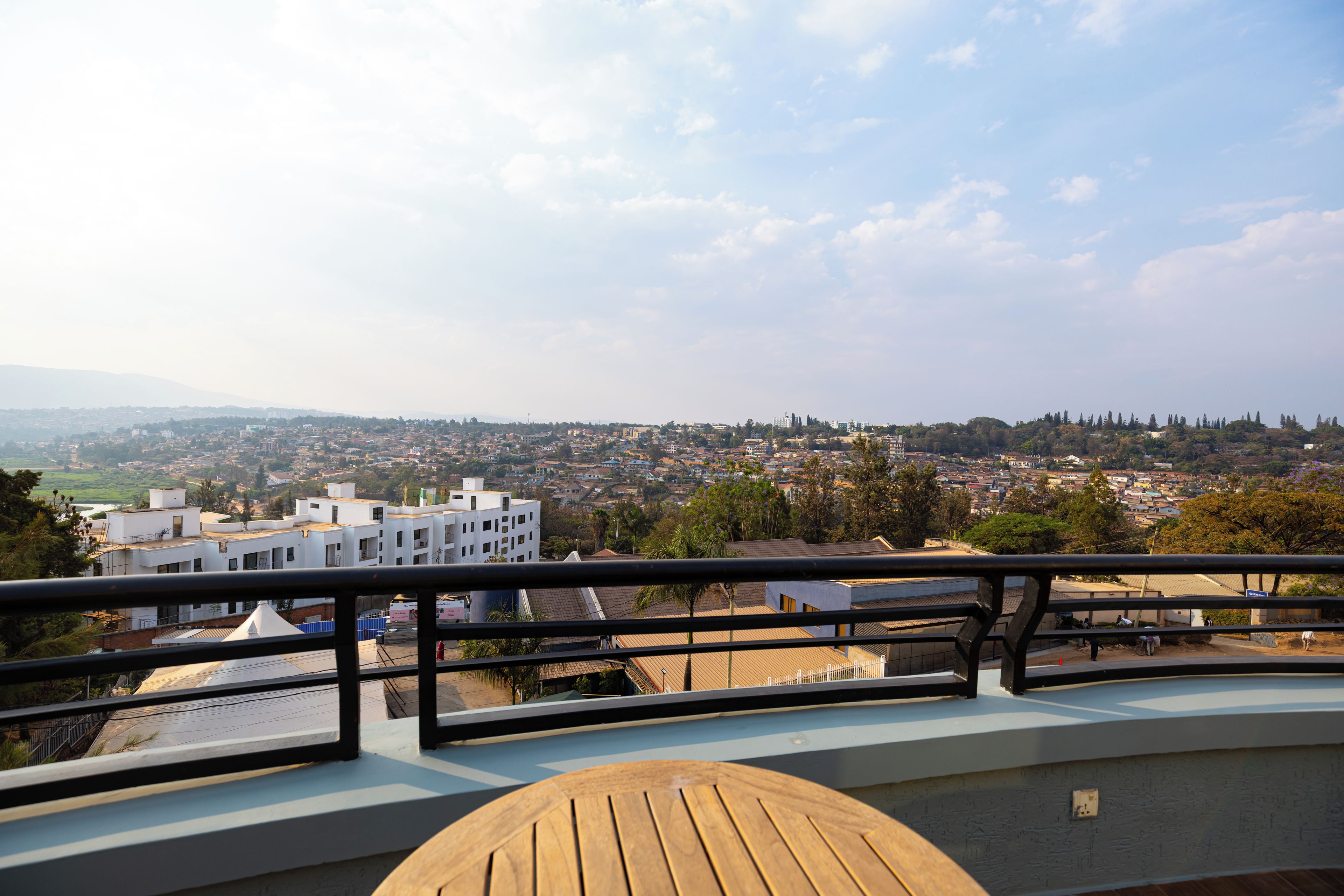 A balcony with a view of a cityscape, including buildings and greenery.