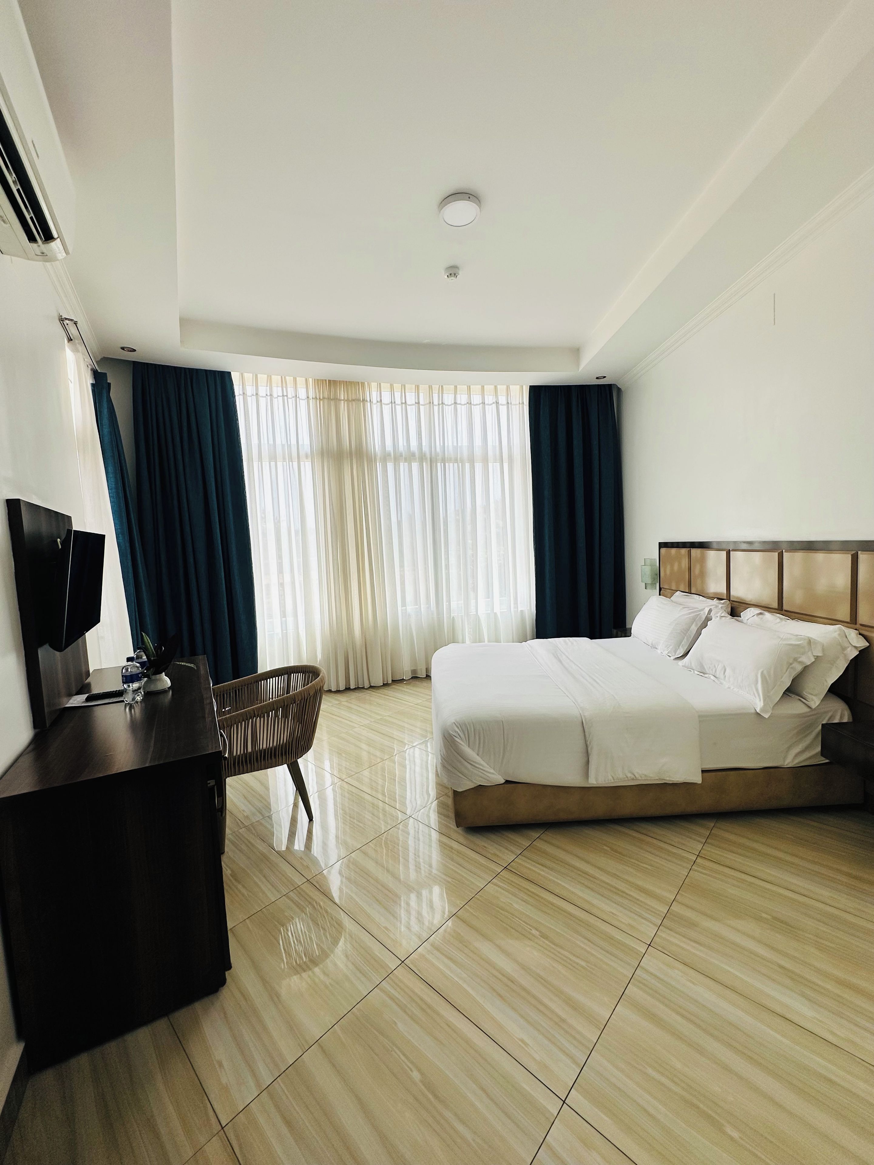 Une chambre d’hôtel avec un lit, un bureau, une chaise et un téléviseur.