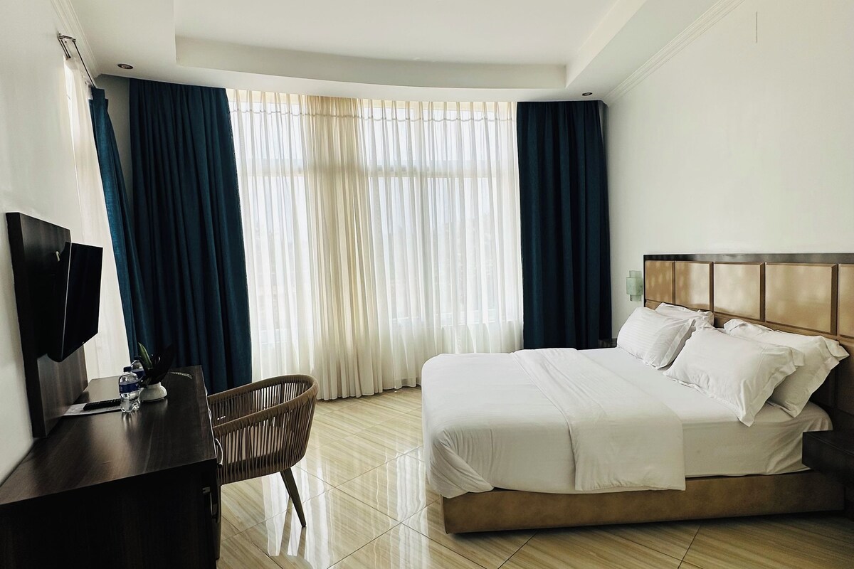 Ein Hotelzimmer mit Bett, Schreibtisch, Stuhl und Fernseher.