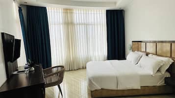 Une chambre d’hôtel avec un lit, un bureau, une chaise et un téléviseur.
