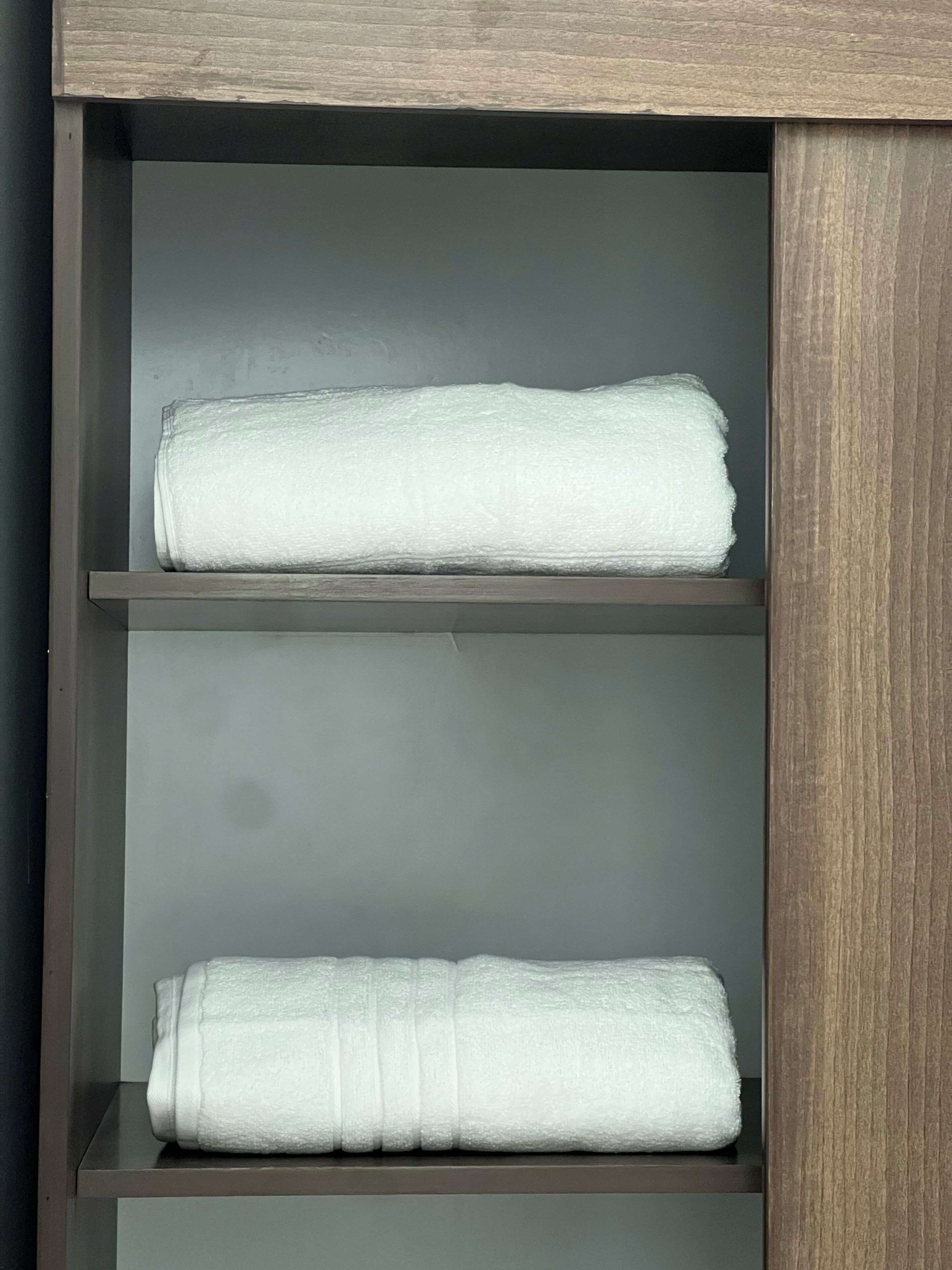 A shelf with two folded white towels.