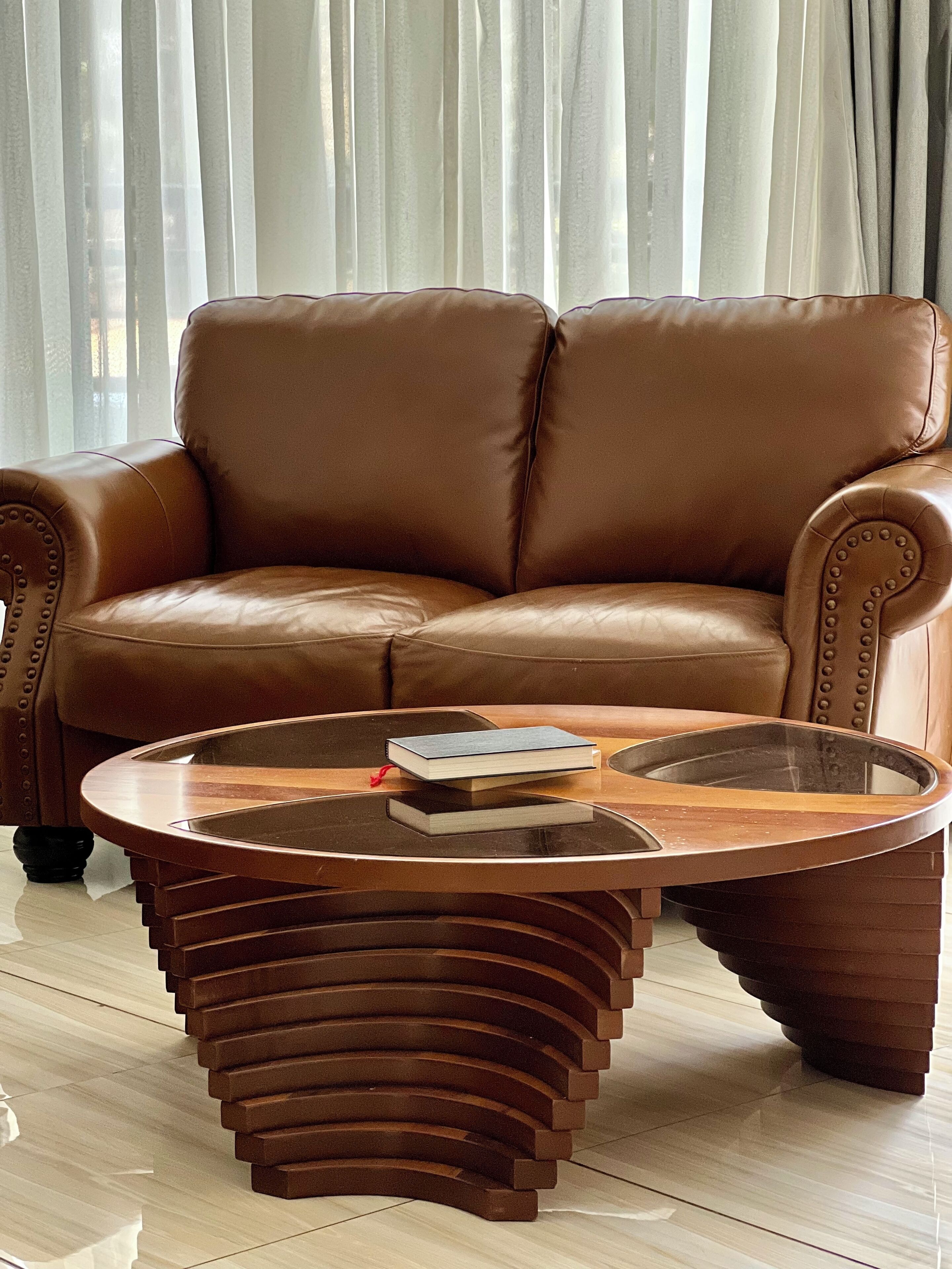 Un canapé en cuir marron, avec une table basse en verre devant.