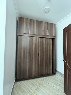 Ein Zimmer mit großem Kleiderschrank, einer Tür und Fliesenboden.