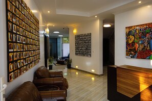 A lobby with a seating area, a wall of framed photographs, and a reception desk. - Eagle View Kimi (Kigali)