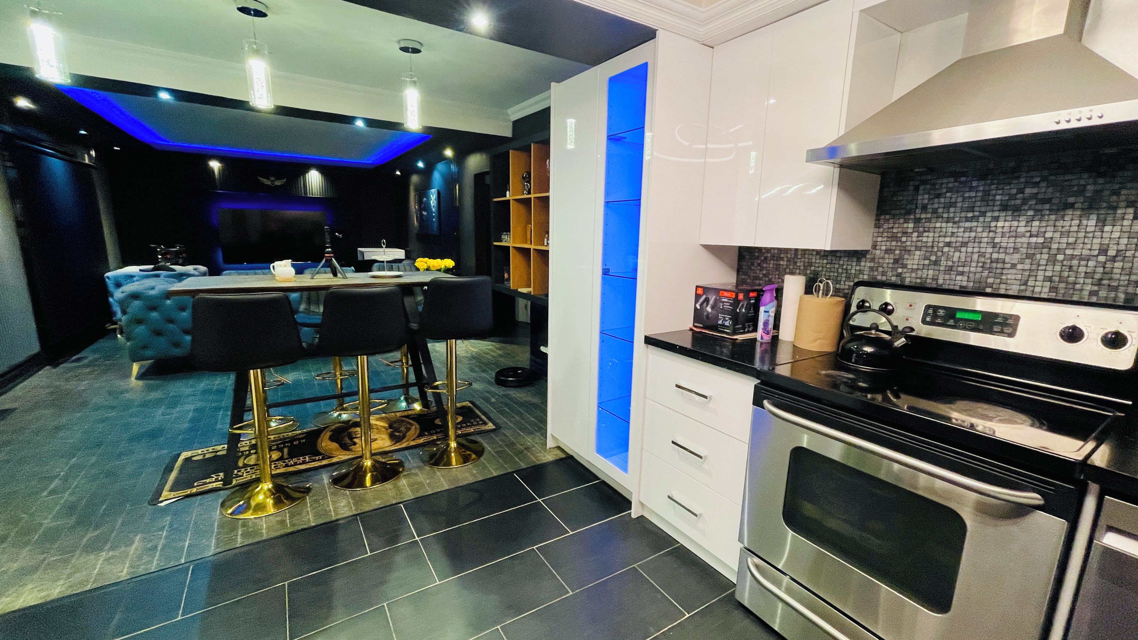 A modern kitchen with a built-in oven, a dining area with bar stools, and a blue accent wall.