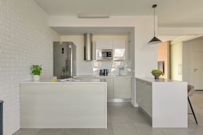 Una cocina moderna con una isla central, electrodomésticos de acero inoxidable y una lámpara colgante.