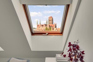 Ein Zimmer mit Dachfenster und Blick auf ein historisches Gebäude mit mehreren Türmen.