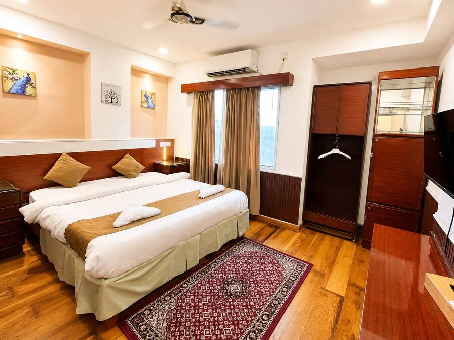 Habitación de hotel con cama doble, armario de madera, televisor y ventana con cortinas.