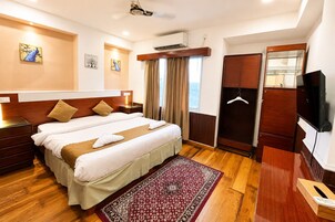 Habitación de hotel con cama doble, armario de madera, televisor y ventana con cortinas.
