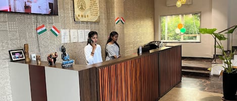 A reception desk with a patterned wall, a television screen, and flags.