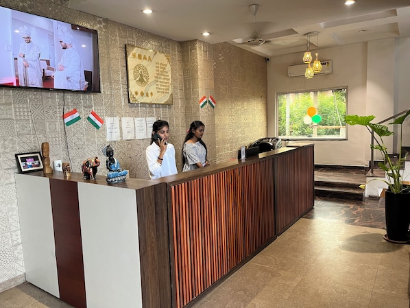 A reception desk with a patterned wall, a television screen, and flags.
