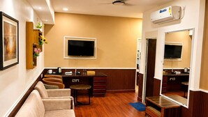 Une chambre d’hôtel équipée d’un canapé, d’une télévision, d’un bureau et d’un miroir.