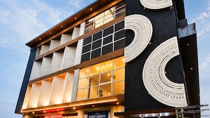 Un bâtiment moderne avec une enseigne indiquant le restaurant « Sweet Greens », un escalier et un ciel dégagé.