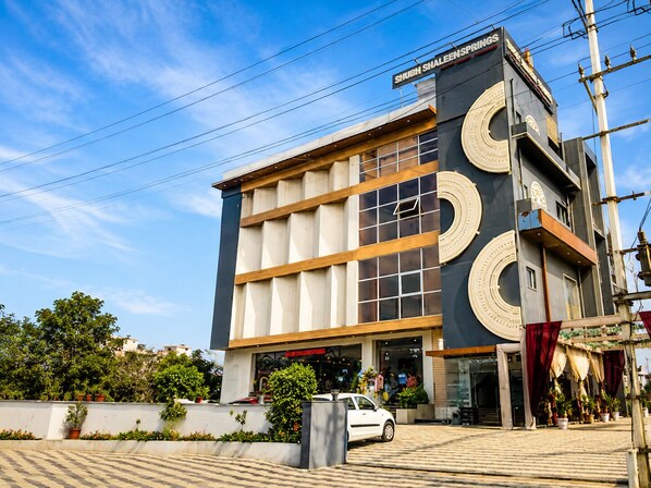 Un edificio moderno con un letrero destacado que dice 'SHUBH SHALEEN SPRINGS'.
