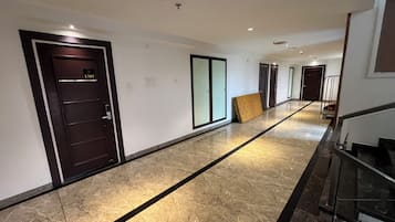 Un pasillo con suelo de mármol, puertas y una escalera.