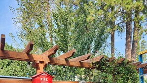 Een houten hek met een rode brandkraan, een fiets en een houten pergola.