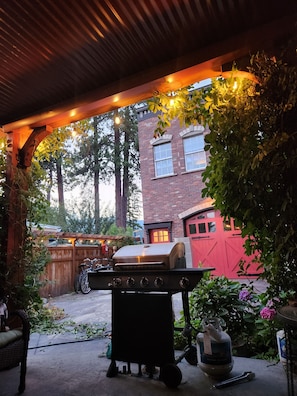 A covered outdoor area with a barbecue grill, a gas cylinder, and a bicycle.