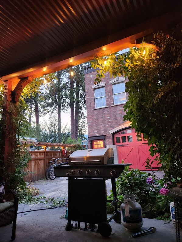 A covered outdoor area with a barbecue grill, a gas cylinder, and a bicycle.