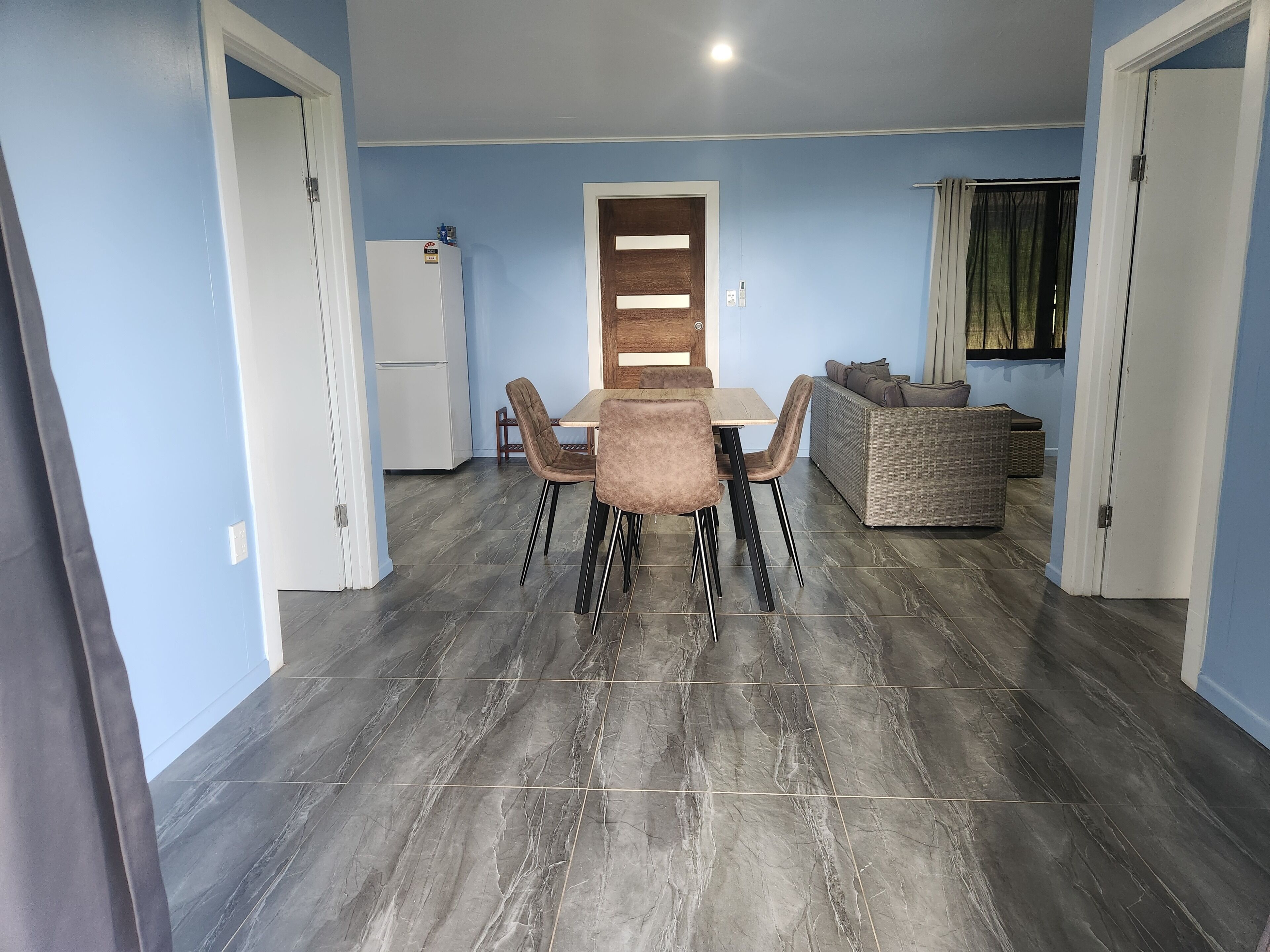 A dining area with a table and chairs, a refrigerator, and a sofa.