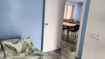 A bedroom with a bed, a wardrobe, and a door leading to a dining area.