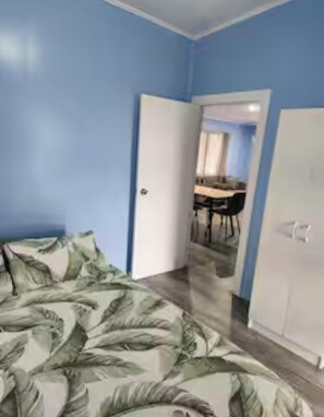 A bedroom with a bed, a wardrobe, and a door leading to a dining area. - Peaceful 2BR Retreat with AC Near Muri Lagoon  (Rarotonga)