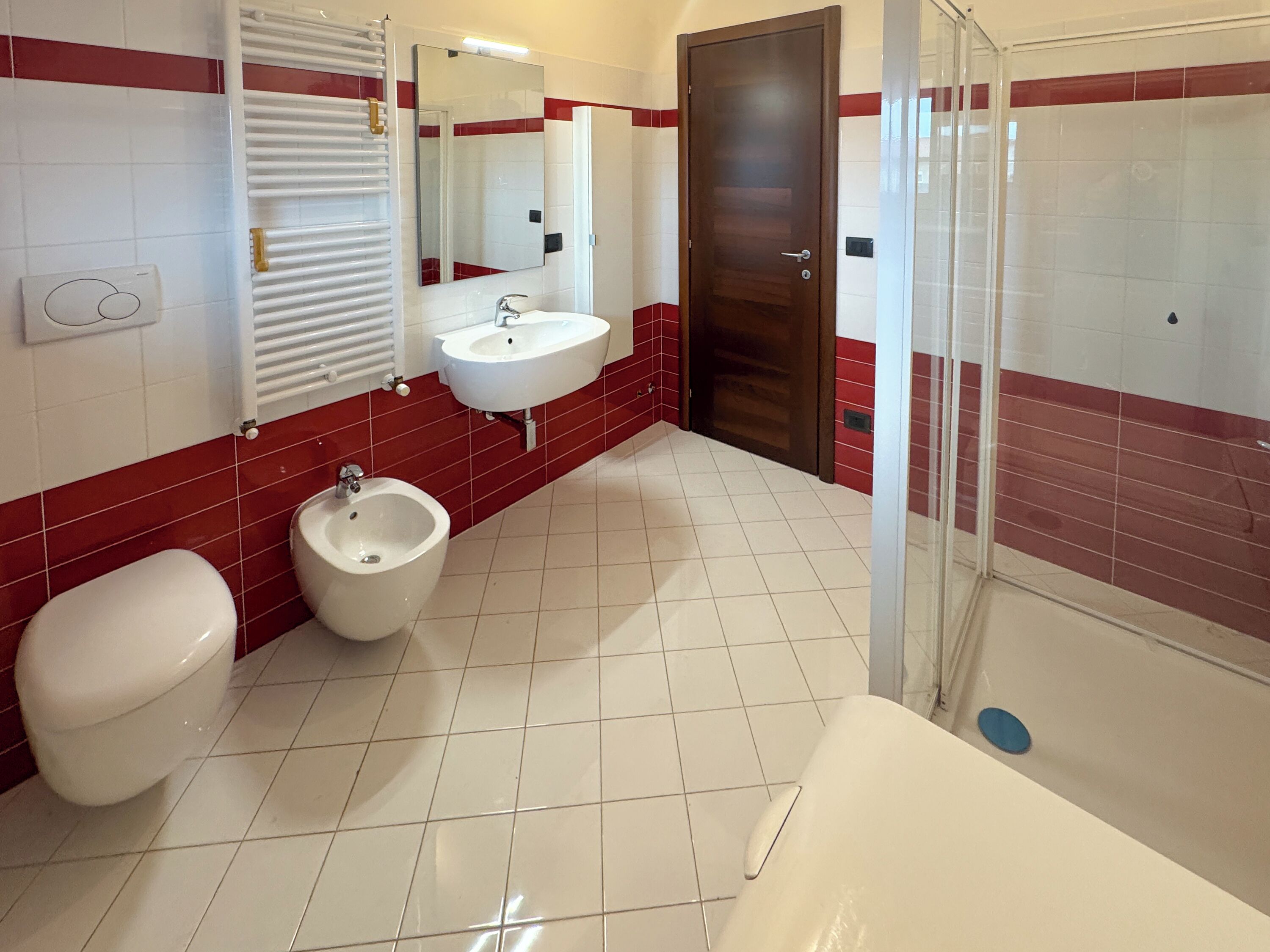 Ein Badezimmer mit Toilette, Bidet, Waschbecken und Duschbereich.
