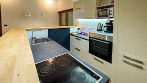 Cocina compacta con una placa de inducción negra, microondas, hervidor y tostadora.