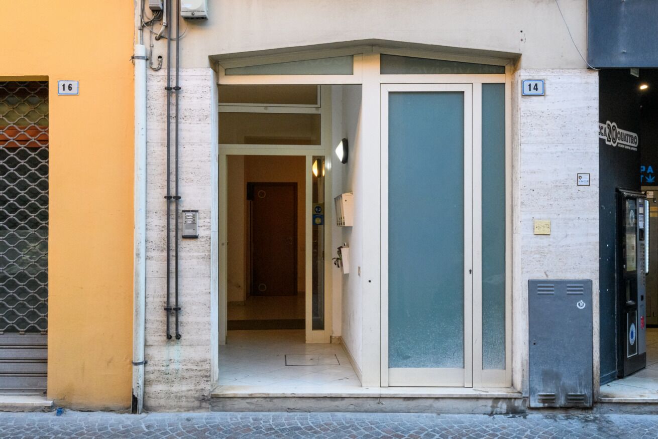 Une entrée d’immeuble avec une porte portant le numéro « 16 » et une enseigne indiquant le numéro « 14 » au-dessus.