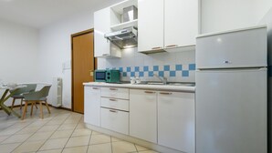 Eine moderne Küche mit weißen Schränken, einer eingebauten Mikrowelle und einem Kühlschrank.